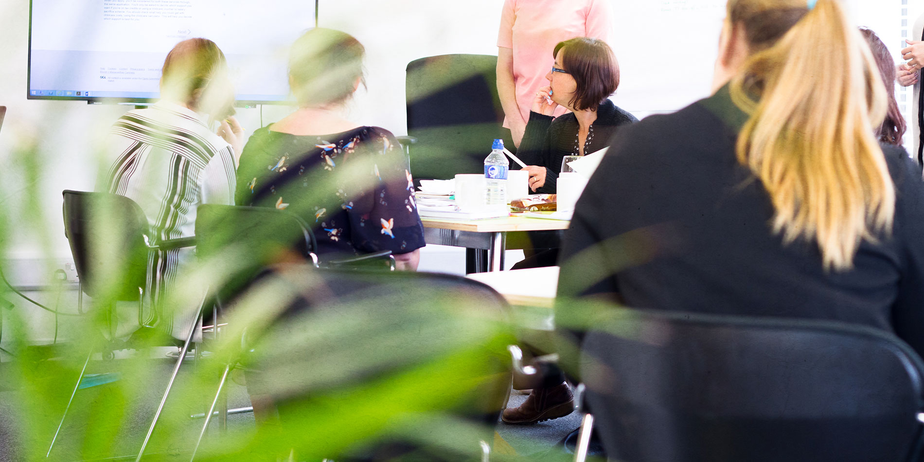 People sat around conference table looking at presentation screen